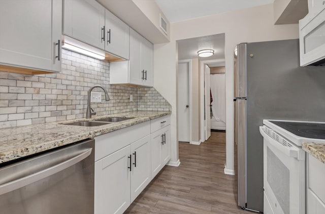 3220 69th St Unit B8, Galveston, TX 77551 - kitchen with white appliances, a sink, light wood-style floors, decorative backsplash, and white cabinets