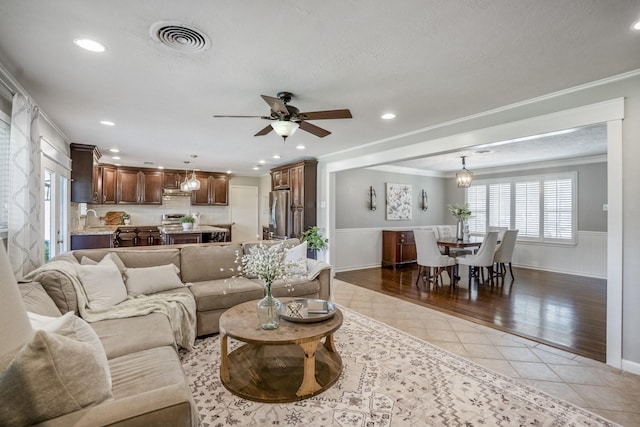 10207 Chatterton Dr, Houston, TX 77043 - living area featuring ornamental molding, light tile patterned flooring, ceiling fan, plenty of natural light, and a wainscoted wall