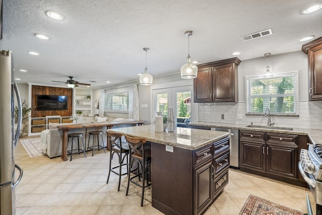 10207 Chatterton Dr, Houston, TX 77043 - kitchen with a sink, open floor plan, stainless steel appliances, a textured ceiling, and a breakfast bar