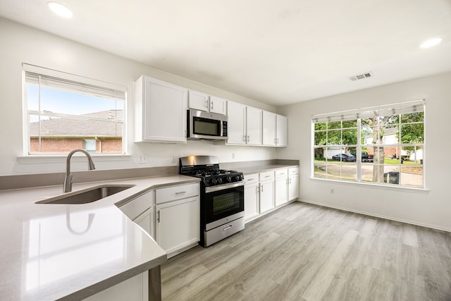 3107 Snug Harbour Ct, Katy, TX 77449 - kitchen with appliances with stainless steel finishes, a sink, light wood-style floors, white cabinets, and light countertops