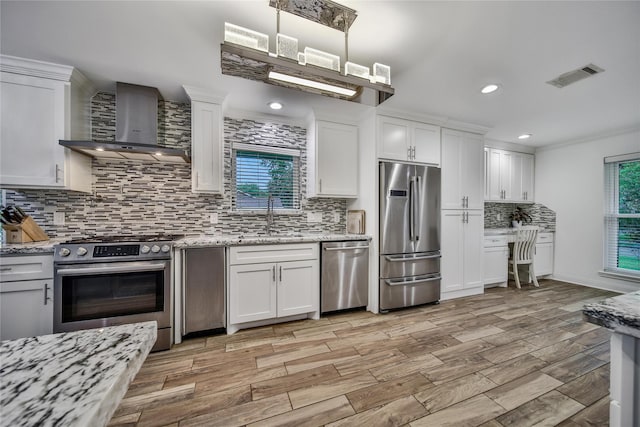 963 Thornton Rd, Houston, TX 77018 - kitchen featuring appliances with stainless steel finishes, wall chimney exhaust hood, backsplash, white cabinets, and recessed lighting