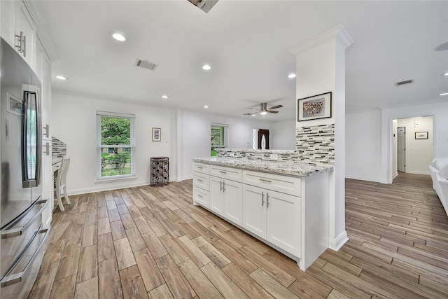 963 Thornton Rd, Houston, TX 77018 - kitchen featuring stainless steel refrigerator, light wood-style floors, a ceiling fan, white cabinets, and light stone counters