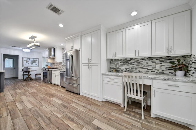 963 Thornton Rd, Houston, TX 77018 - kitchen featuring appliances with stainless steel finishes, wall chimney exhaust hood, tasteful backsplash, white cabinets, and recessed lighting