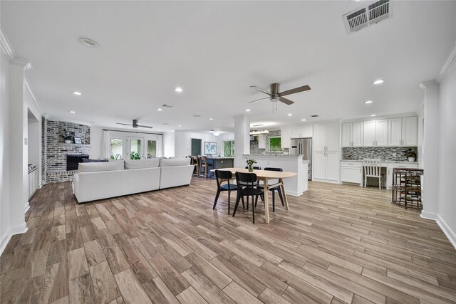 963 Thornton Rd, Houston, TX 77018 - living room with ceiling fan, a brick fireplace, ornamental molding, recessed lighting, and light wood-style flooring