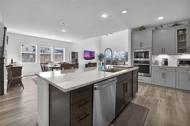 11930 Mccallister Run Dr, Humble, TX 77346 - kitchen with stainless steel appliances, a sink, light wood-style flooring, a center island with sink, and recessed lighting