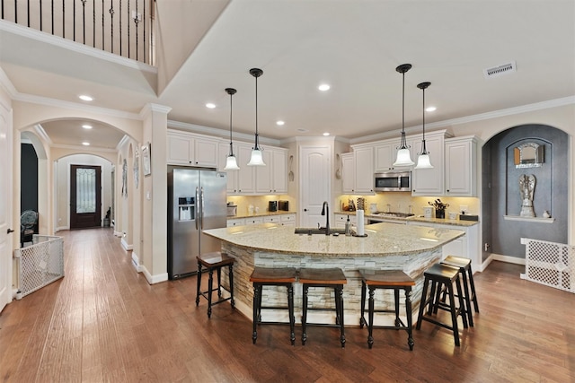 18110 Berry Garden Ln, Spring, TX 77379 - kitchen featuring appliances with stainless steel finishes, arched walkways, a sink, baseboards, and a large island