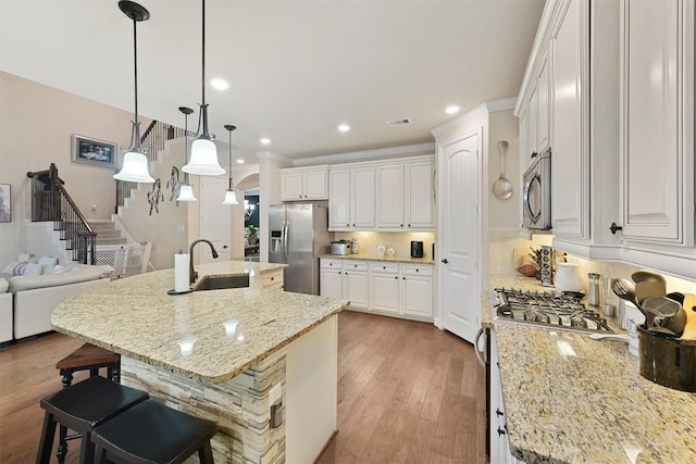18110 Berry Garden Ln, Spring, TX 77379 - kitchen featuring appliances with stainless steel finishes, a sink, a breakfast bar area, light wood-style floors, and backsplash
