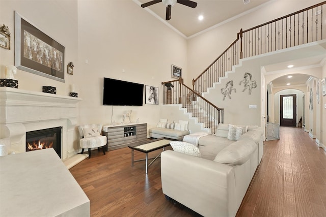 18110 Berry Garden Ln, Spring, TX 77379 - living room with arched walkways, a towering ceiling, a ceiling fan, ornamental molding, and wood finished floors