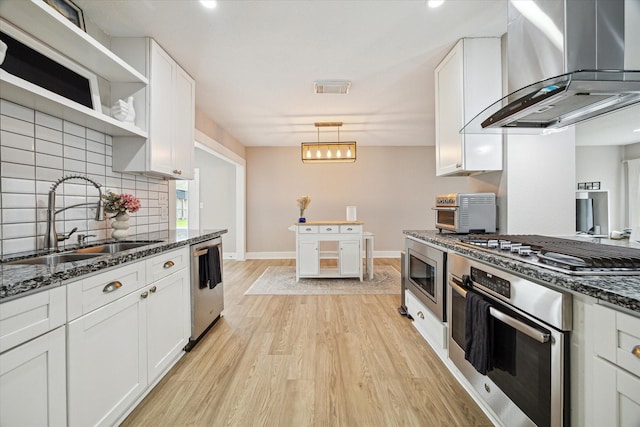 15818 Acapulco Dr, Jersey Village, TX 77040 - kitchen with wall chimney exhaust hood, stainless steel appliances, a sink, light wood-style flooring, and tasteful backsplash