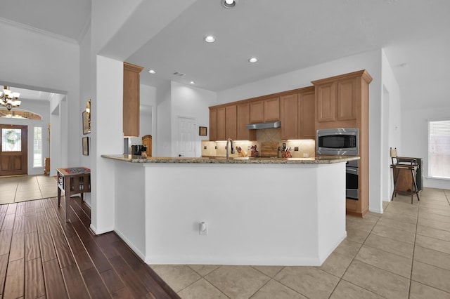 16923 Fondness Park Dr, Spring, TX 77379 - kitchen with stainless steel microwave, under cabinet range hood, light stone countertops, backsplash, and recessed lighting