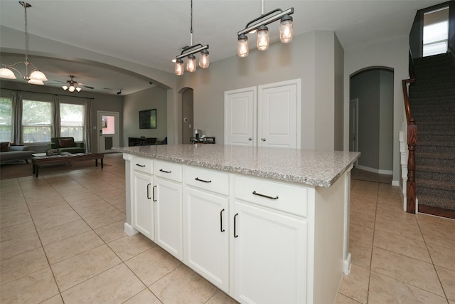 16826 Paynes Creek Dr, Cypress, TX 77433 - kitchen with arched walkways, light tile patterned floors, open floor plan, ceiling fan, and light stone counters