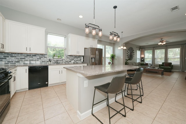 16826 Paynes Creek Dr, Cypress, TX 77433 - kitchen with black appliances, light tile patterned floors, open floor plan, backsplash, and a kitchen island