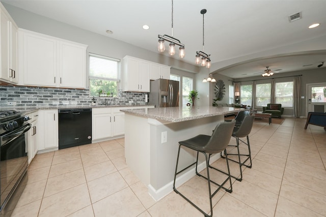 16826 Paynes Creek Dr, Cypress, TX 77433 - kitchen featuring black appliances, light tile patterned flooring, open floor plan, decorative backsplash, and a center island