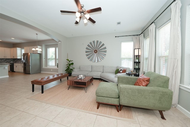 16826 Paynes Creek Dr, Cypress, TX 77433 - living room with light tile patterned floors, ceiling fan, baseboards, arched walkways, and a chandelier