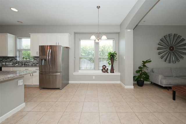 16826 Paynes Creek Dr, Cypress, TX 77433 - kitchen featuring stainless steel fridge, light stone counters, backsplash, light tile patterned floors, and white cabinetry