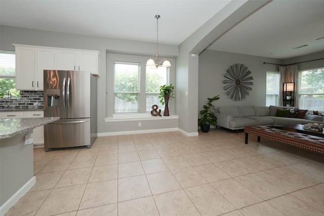 16826 Paynes Creek Dr, Cypress, TX 77433 - kitchen featuring stainless steel fridge, open floor plan, decorative backsplash, a chandelier, and light stone counters