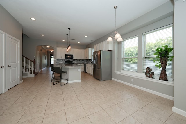 16826 Paynes Creek Dr, Cypress, TX 77433 - kitchen with stainless steel fridge, black microwave, arched walkways, tasteful backsplash, and a breakfast bar area