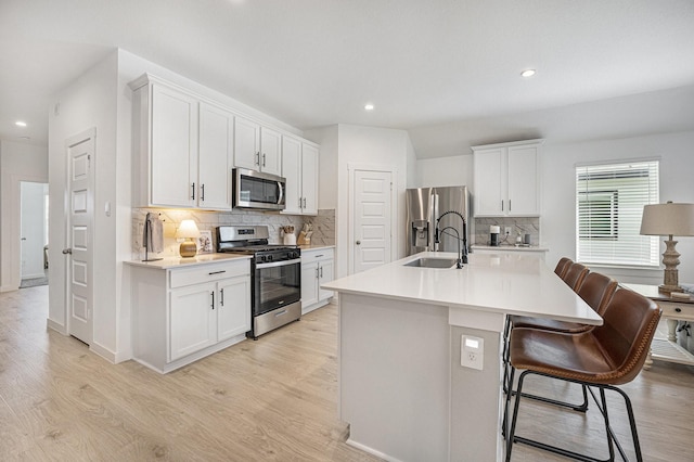 31723 Kellan Grove Ct, Fulshear, TX 77441 - kitchen featuring appliances with stainless steel finishes, light wood-type flooring, tasteful backsplash, a sink, and light countertops