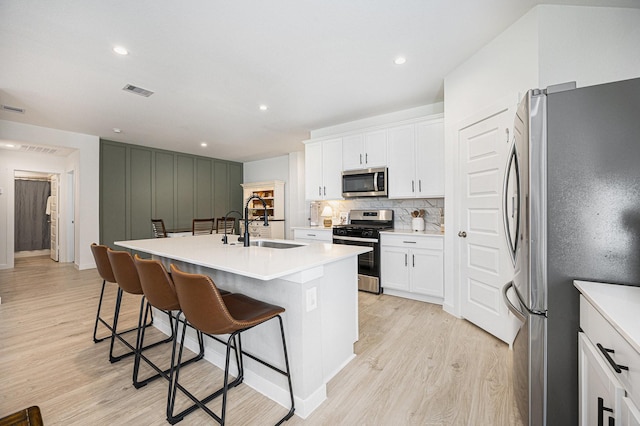 31723 Kellan Grove Ct, Fulshear, TX 77441 - kitchen with stainless steel appliances, a sink, light wood-type flooring, a kitchen breakfast bar, and an island with sink