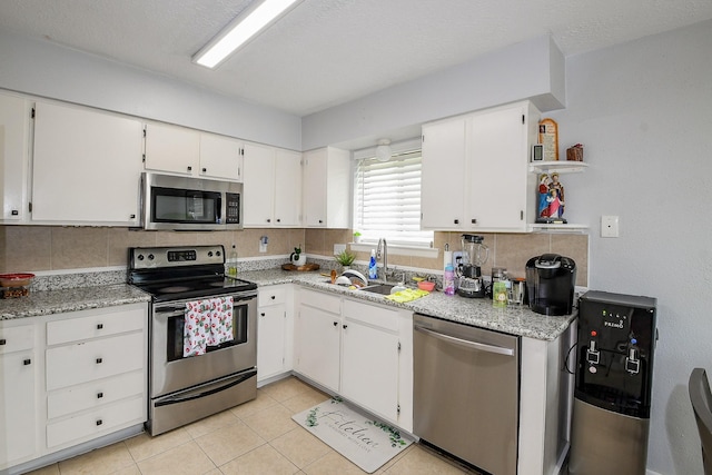 4623 Tealgate Dr, Spring, TX 77373 - kitchen with stainless steel appliances, open shelves, backsplash, white cabinetry, and a sink