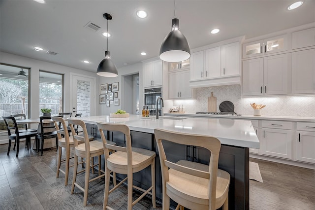 6718 Mirabeau Ln, Katy, TX 77493 - kitchen featuring a sink, stainless steel oven, light countertops, tasteful backsplash, and a center island with sink