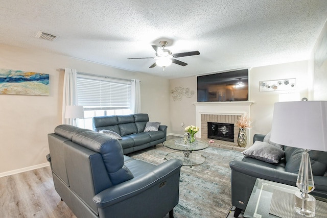 19727 Teller Blvd, Spring, TX 77388 - living room featuring wood finished floors, ceiling fan, a brick fireplace, a textured ceiling, and baseboards