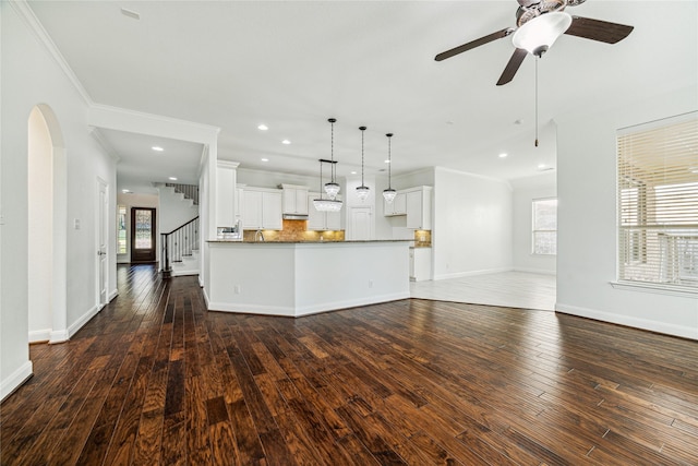 1811 Leela Springs Dr, Conroe, TX 77304 - unfurnished living room featuring baseboards, dark wood finished floors, a ceiling fan, crown molding, and arched walkways