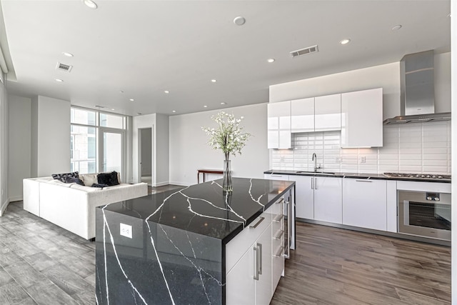 4521 San Felipe St Unit 1203, Houston, TX 77027 - kitchen with appliances with stainless steel finishes, wall chimney range hood, a sink, dark wood-style floors, and recessed lighting