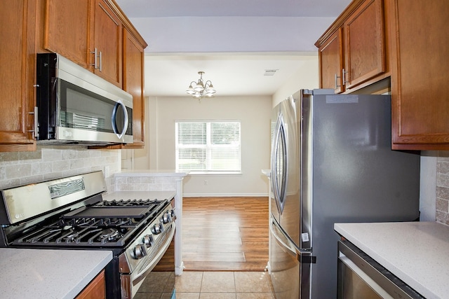 15027 Silhouette Ridge Dr, Humble, TX 77396 - kitchen with stainless steel appliances, brown cabinets, and backsplash