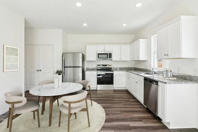 10238 Red Orchid Dr, Houston, TX 77016 - kitchen featuring appliances with stainless steel finishes, a sink, white cabinetry, dark wood-style flooring, and recessed lighting