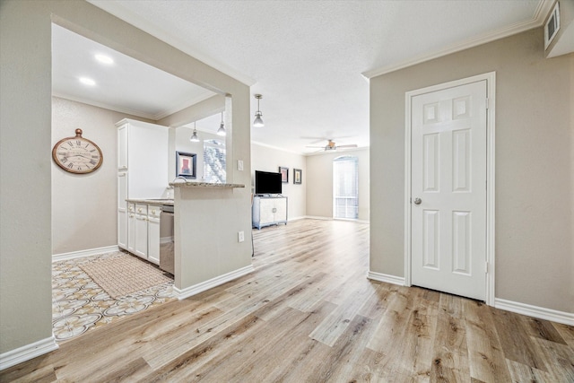4649 Wild Indigo St Unit 340, Houston, TX 77027 - kitchen with crown molding, white cabinetry, ceiling fan, light wood finished floors, and baseboards