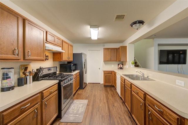 2910 Yearling Colt Ct, Houston, TX 77038 - kitchen featuring stainless steel appliances, a sink, under cabinet range hood, wood finished floors, and light countertops