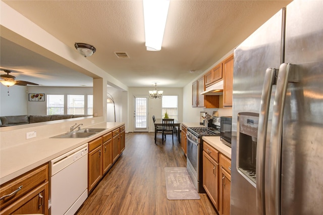 2910 Yearling Colt Ct, Houston, TX 77038 - kitchen with appliances with stainless steel finishes, a sink, dark wood-style flooring, under cabinet range hood, and brown cabinets