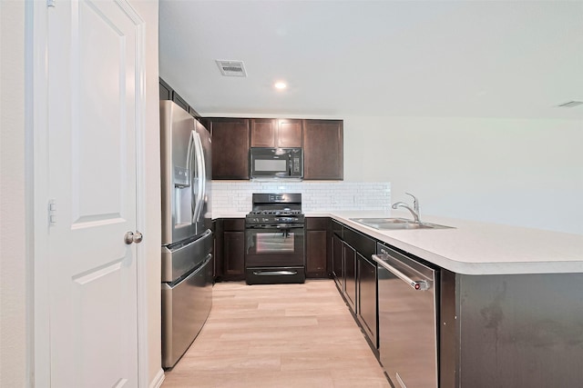 14627 Woodcott Warren Way, Pearland, TX 77545 - kitchen with black appliances, a sink, light wood-style floors, light countertops, and a peninsula