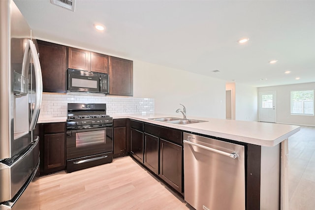 14627 Woodcott Warren Way, Pearland, TX 77545 - kitchen featuring black appliances, a sink, a peninsula, light countertops, and light wood-style floors