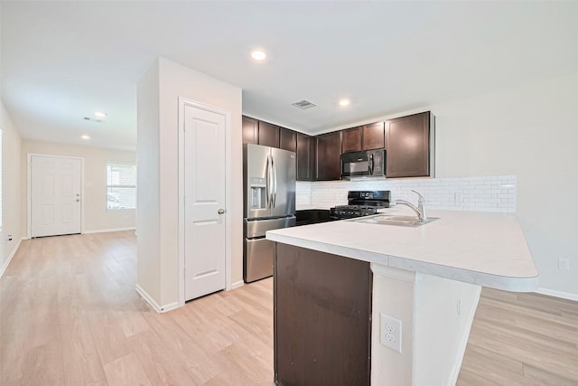 14627 Woodcott Warren Way, Pearland, TX 77545 - kitchen with black appliances, a sink, dark brown cabinets, a peninsula, and light wood-type flooring