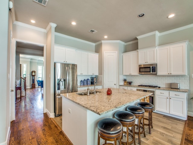 221 W 25th St Unit A, Houston, TX 77008 - kitchen featuring stainless steel appliances, a sink, an island with sink, light wood-style floors, and white cabinets