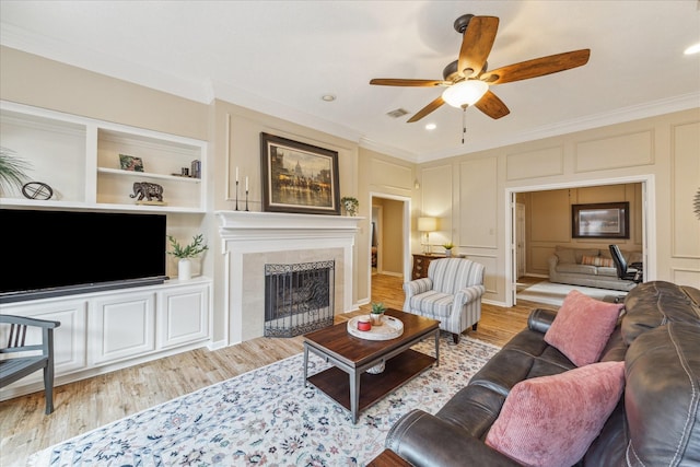 1902 Carriage Brook Way, Houston, TX 77062 - living room featuring crown molding, light wood-style flooring, a ceiling fan, a fireplace, and built in shelves