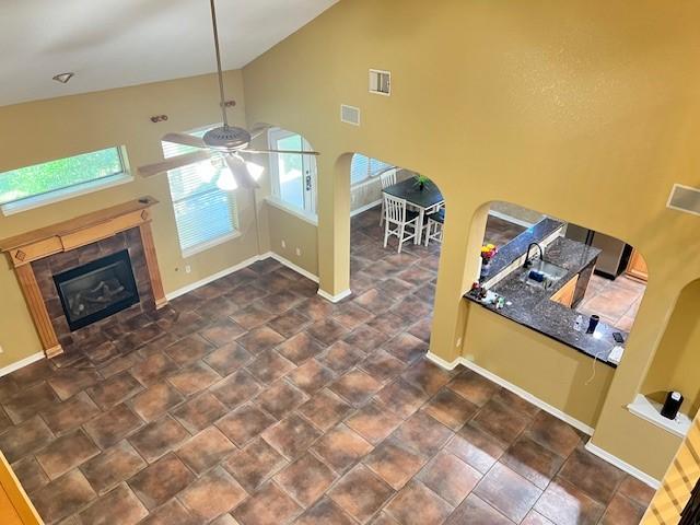 11608 Summer Moon Dr, Pearland, TX 77584 - living room with healthy amount of natural light, ceiling fan, a tiled fireplace, high vaulted ceiling, and arched walkways