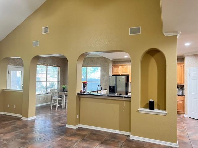 11608 Summer Moon Dr, Pearland, TX 77584 - kitchen with stainless steel fridge with ice dispenser, high vaulted ceiling, healthy amount of natural light, dark countertops, and baseboards