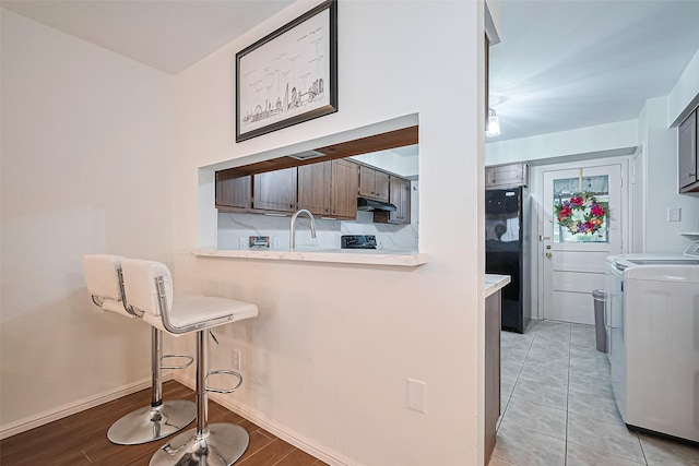 4304 Sherwood Ln Unit 106, Houston, TX 77092 - kitchen with washer and clothes dryer, under cabinet range hood, freestanding refrigerator, a kitchen bar, and light countertops