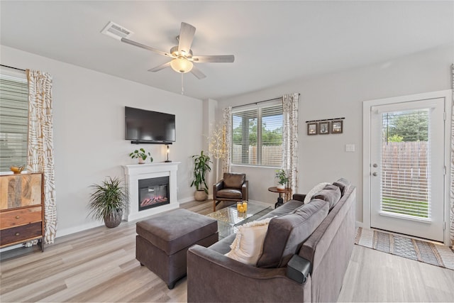 3125 Skyrock Dr, Houston, TX 77063 - living area with light wood-style floors, ceiling fan, a glass covered fireplace, and baseboards