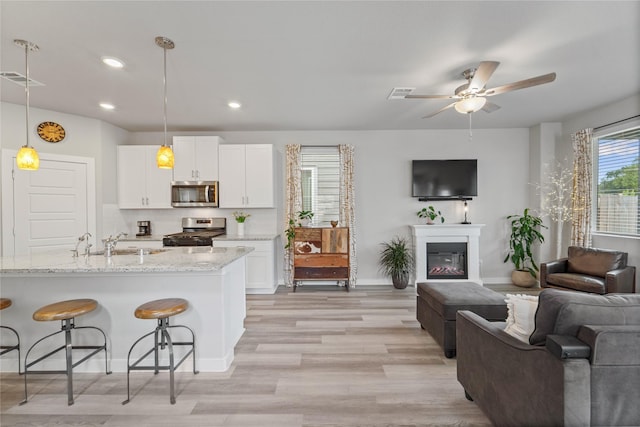3125 Skyrock Dr, Houston, TX 77063 - kitchen with stainless steel appliances, open floor plan, a breakfast bar area, white cabinets, and a sink