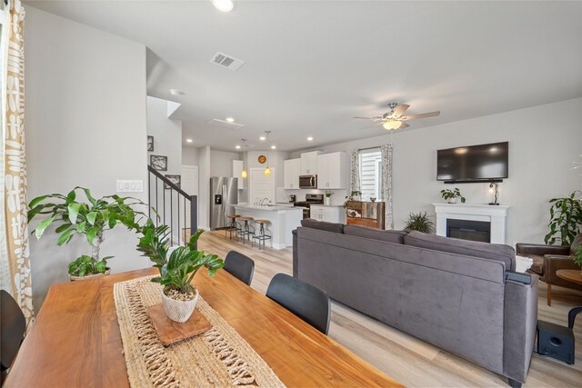 3125 Skyrock Dr, Houston, TX 77063 - dining space with stairway, light wood-style flooring, ceiling fan, a fireplace, and recessed lighting