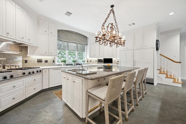 3633 Overbrook Ln, Houston, TX 77027 - kitchen featuring stainless steel gas cooktop, an island with sink, dishwasher, tasteful backsplash, and white cabinetry