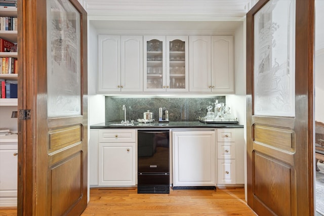 3633 Overbrook Ln, Houston, TX 77027 - indoor wet bar featuring light wood-type flooring, decorative backsplash, and ornamental molding