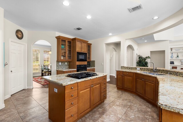 3610 Wellspring Lake Dr, Fulshear, TX 77441 - kitchen with black appliances, a sink, arched walkways, tasteful backsplash, and a center island