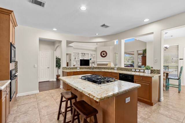 3610 Wellspring Lake Dr, Fulshear, TX 77441 - kitchen featuring a sink, black appliances, a kitchen breakfast bar, a center island, and light stone countertops