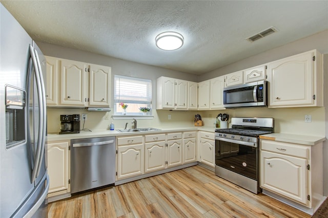14927 Cypress Green Dr, Cypress, TX 77429 - kitchen with stainless steel appliances, light wood-style floors, a sink, light countertops, and a textured ceiling