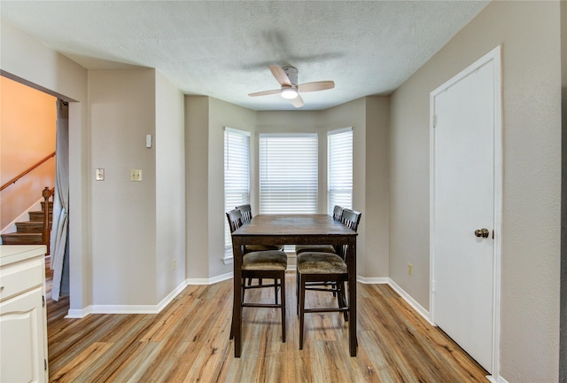 14927 Cypress Green Dr, Cypress, TX 77429 - dining area with ceiling fan, light wood-style flooring, stairway, baseboards, and a textured ceiling